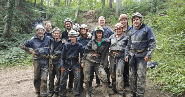 A group of DTSS-3D employees in muddy climbing/spelunking gear